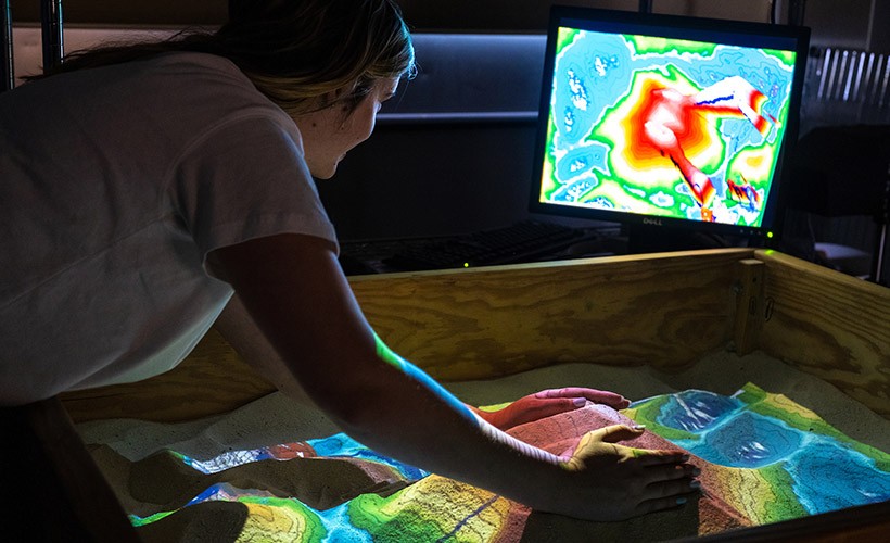 A student works in the augmented reality sandbox.