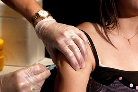 photo of woman with bare arm shown being given vaccine shot by gloved hands