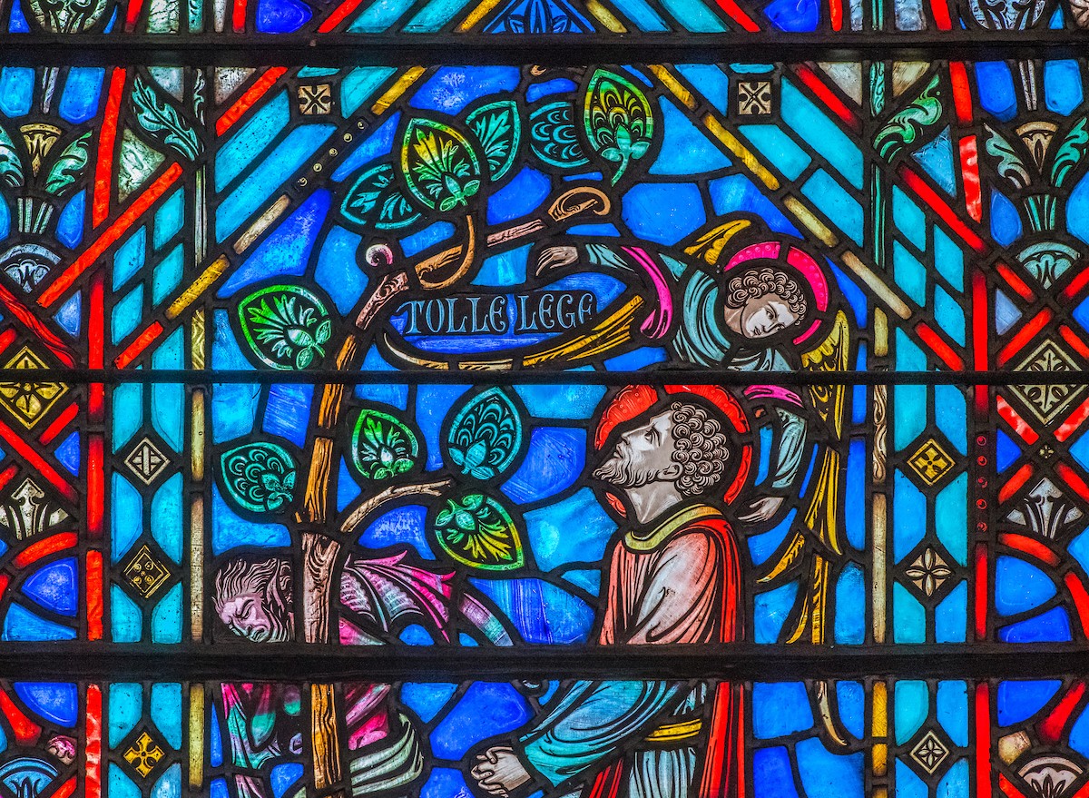 Stained glass window with Augustine and the words "tolle lege"