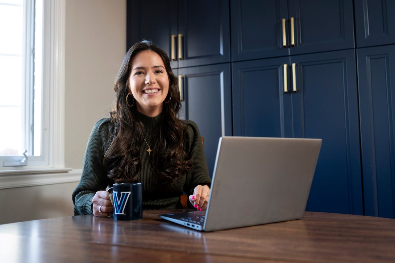 woman sitting at a table in front of a laptop with a coffee mug