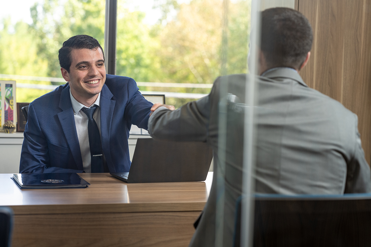 two people shaking hands across a desk