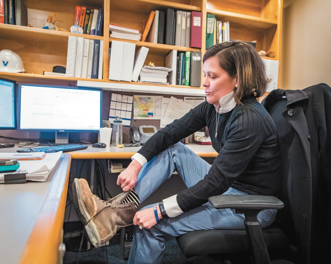 At her desk, Villanova senior project manager Marilou Smith laces up her brown worn construction boots