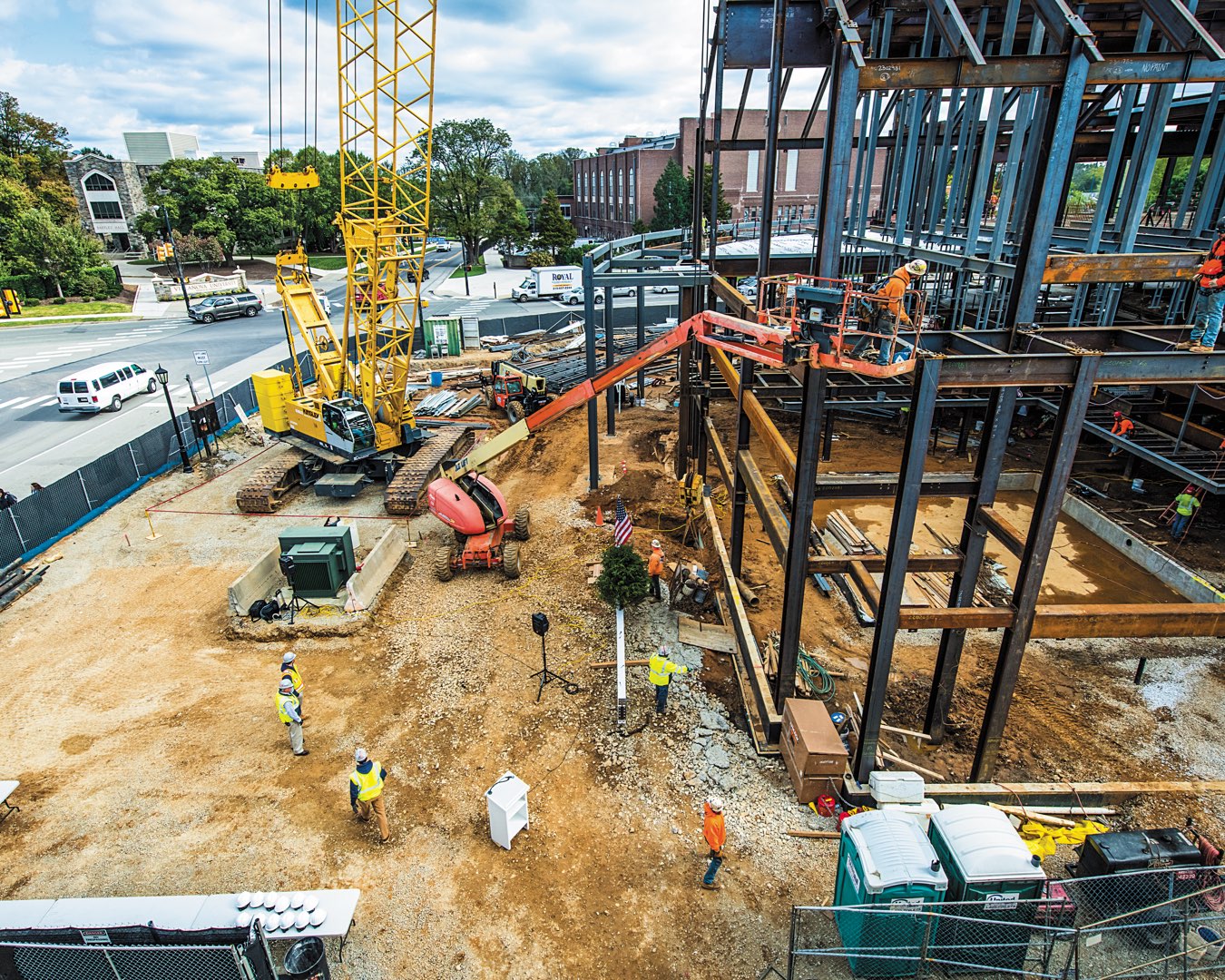 Construction workers and vehicles on site building the steel beam infrastructure for the future Performing Arts Center