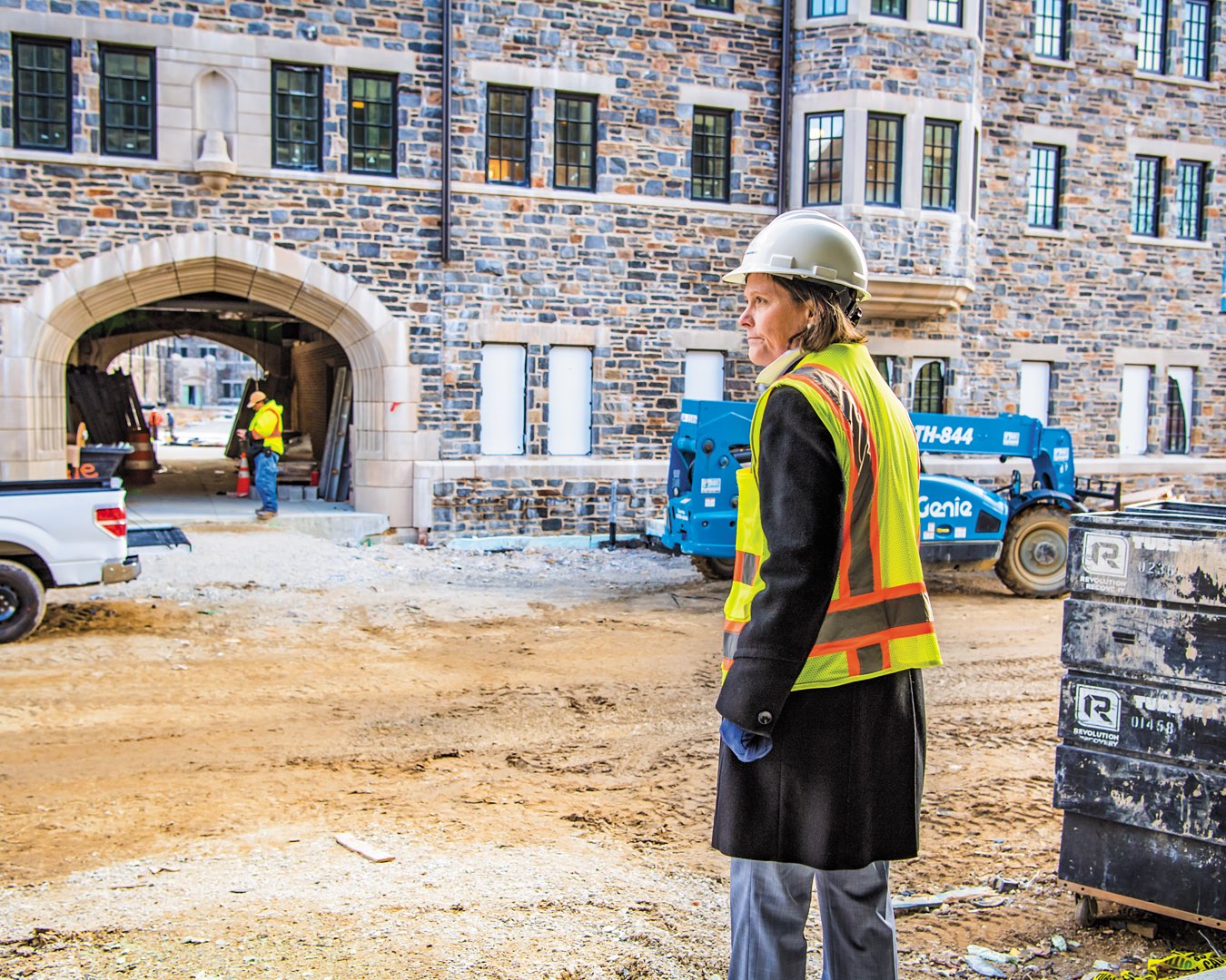 Marilou Smith surveys progress The Commons residence halls site, with construction workers and vehicles in the background