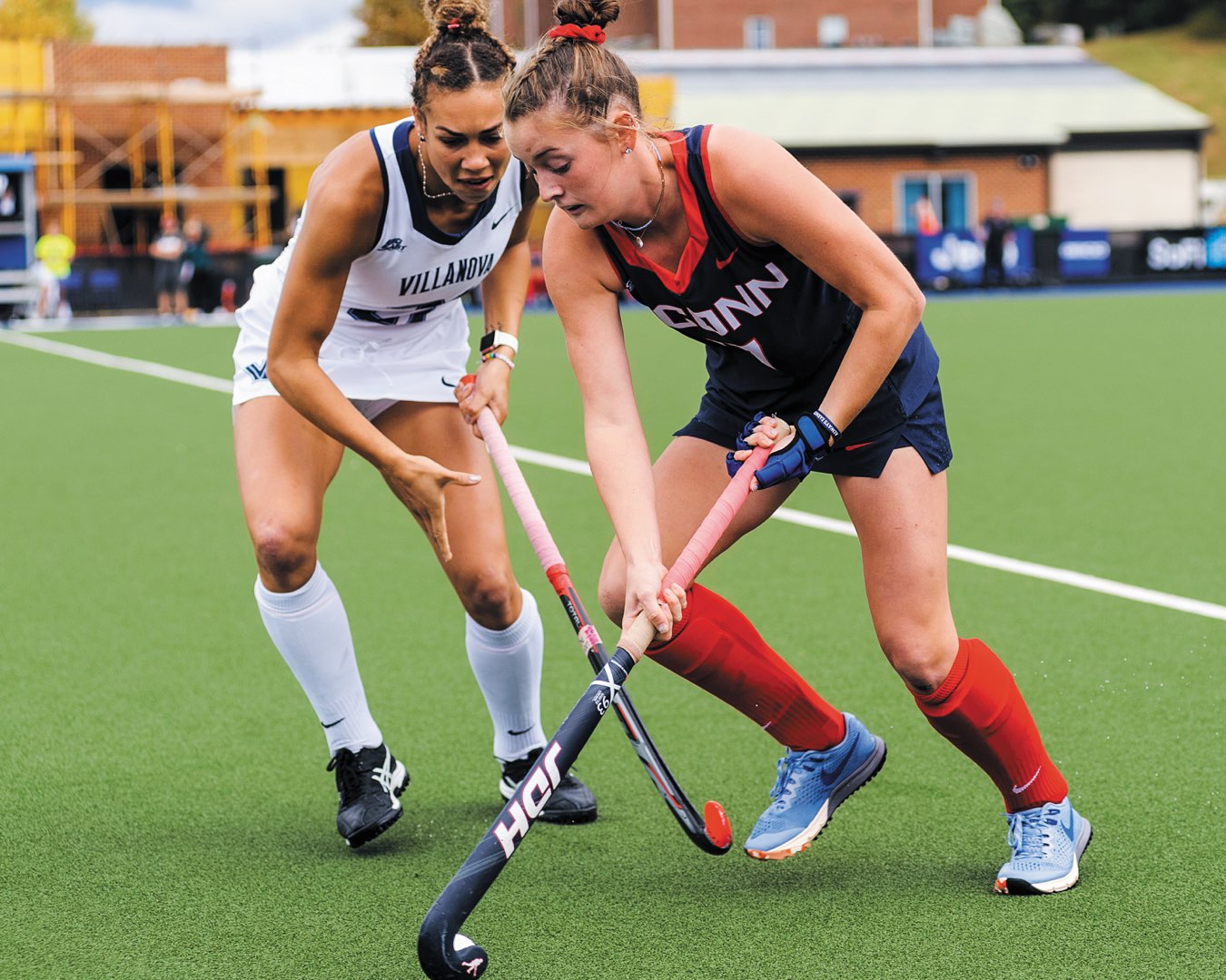 A Villanova Women’s Field Hockey player on the field engaged in play against a player from Connecticut