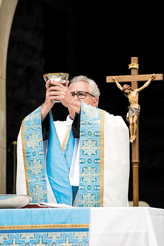 Close-up view of ornate details on Father Peter’s blue, white, and gold liturgical vestment