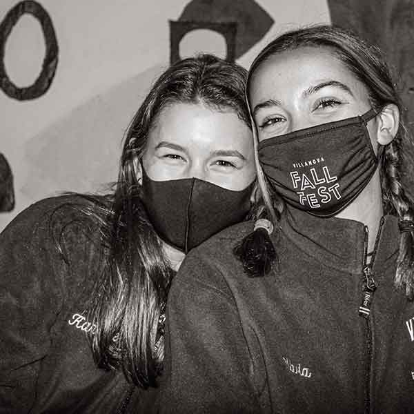 black-and-white photo of two female students smiling behind their face masks