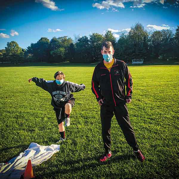 two Special Olympics participants wearing workout clothing pose on a field outside