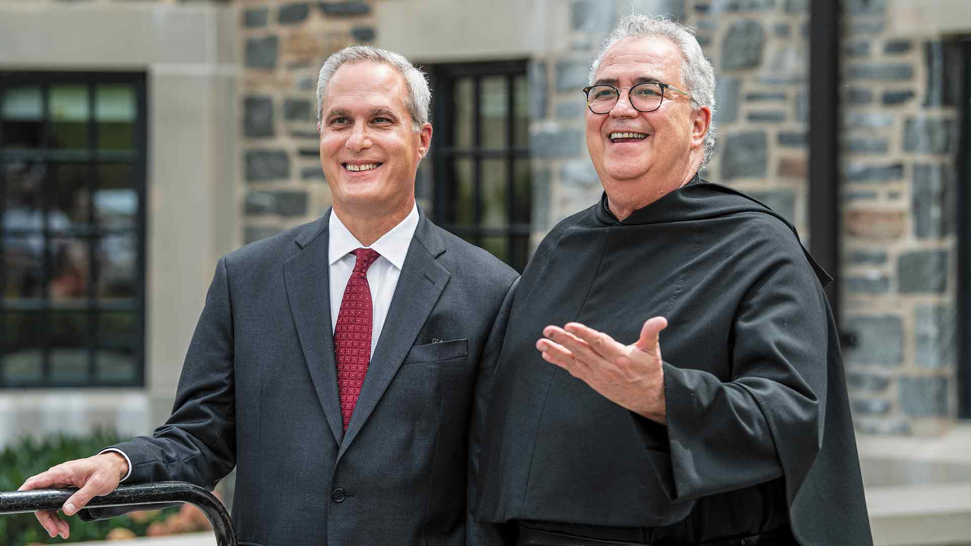 Ken Valosky with Father Peter Donohue standing before the Commons student housing