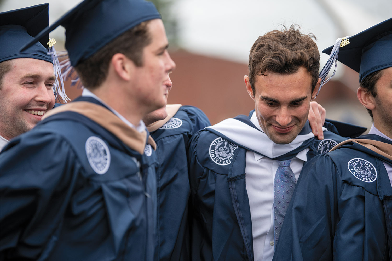 Male Villanova students wearing graduation robes and celebrating.