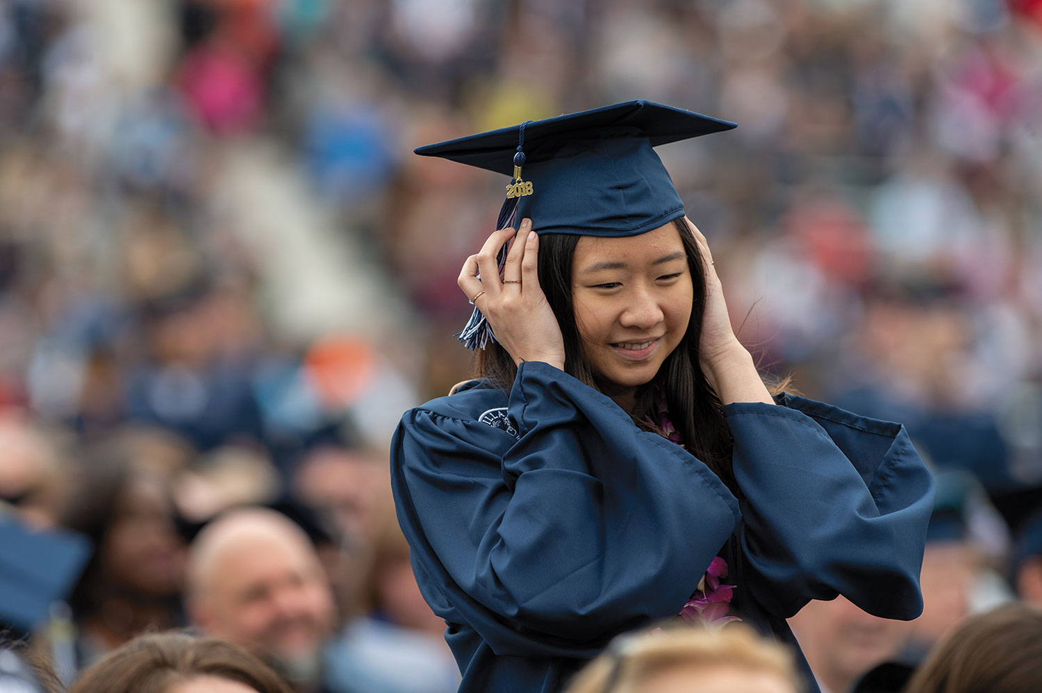 Female Villanova student wearing a graduation robe and smiling.