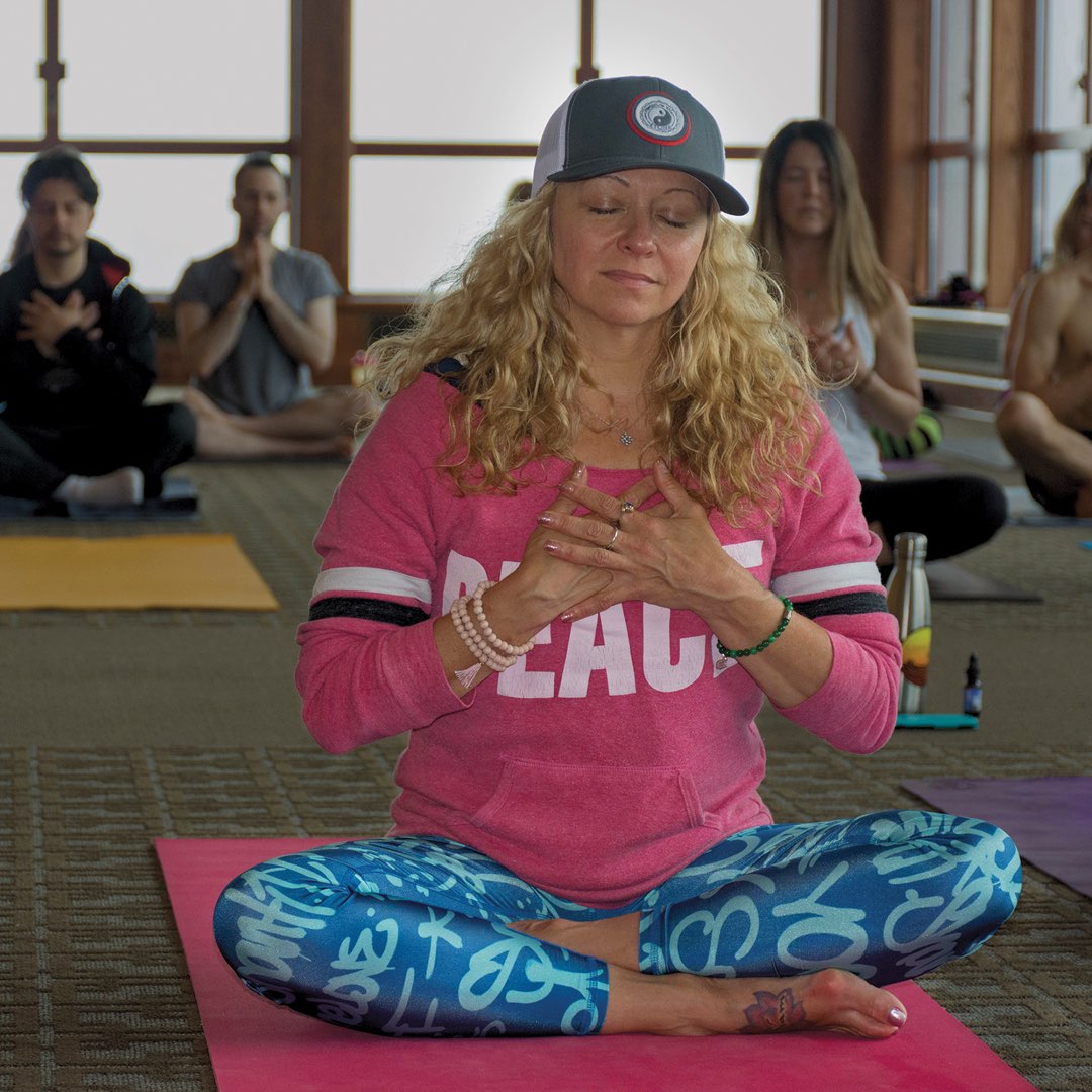 Woman sitting on a mat performing yoga with others.