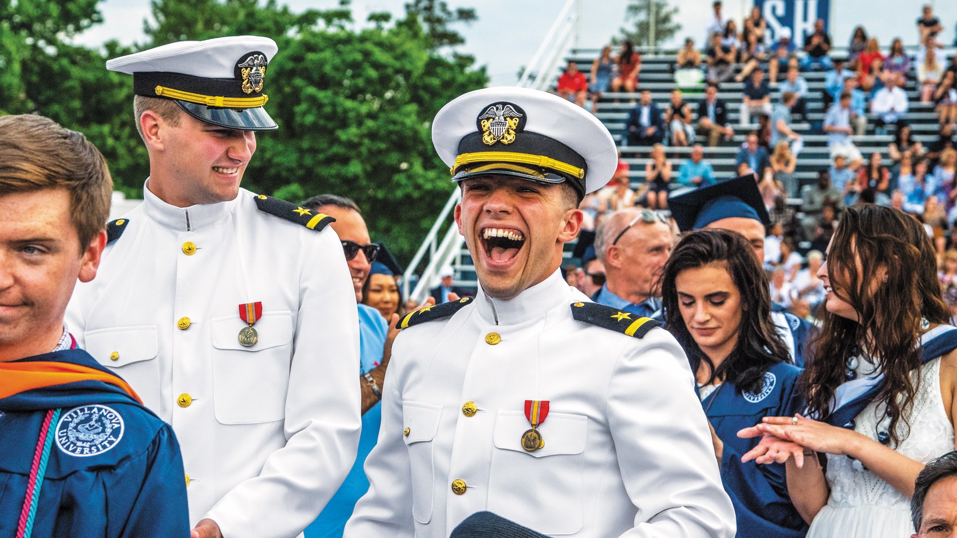 Two graduates wearing their Marine Dress Uniforms, laughing and smiling on Graduation Day