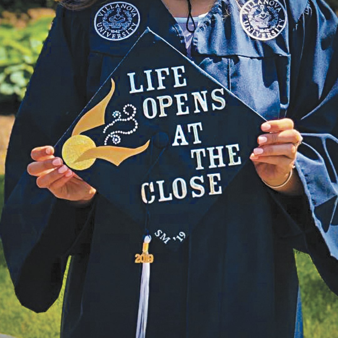 Student holding cap that reads “Life opens at the close”