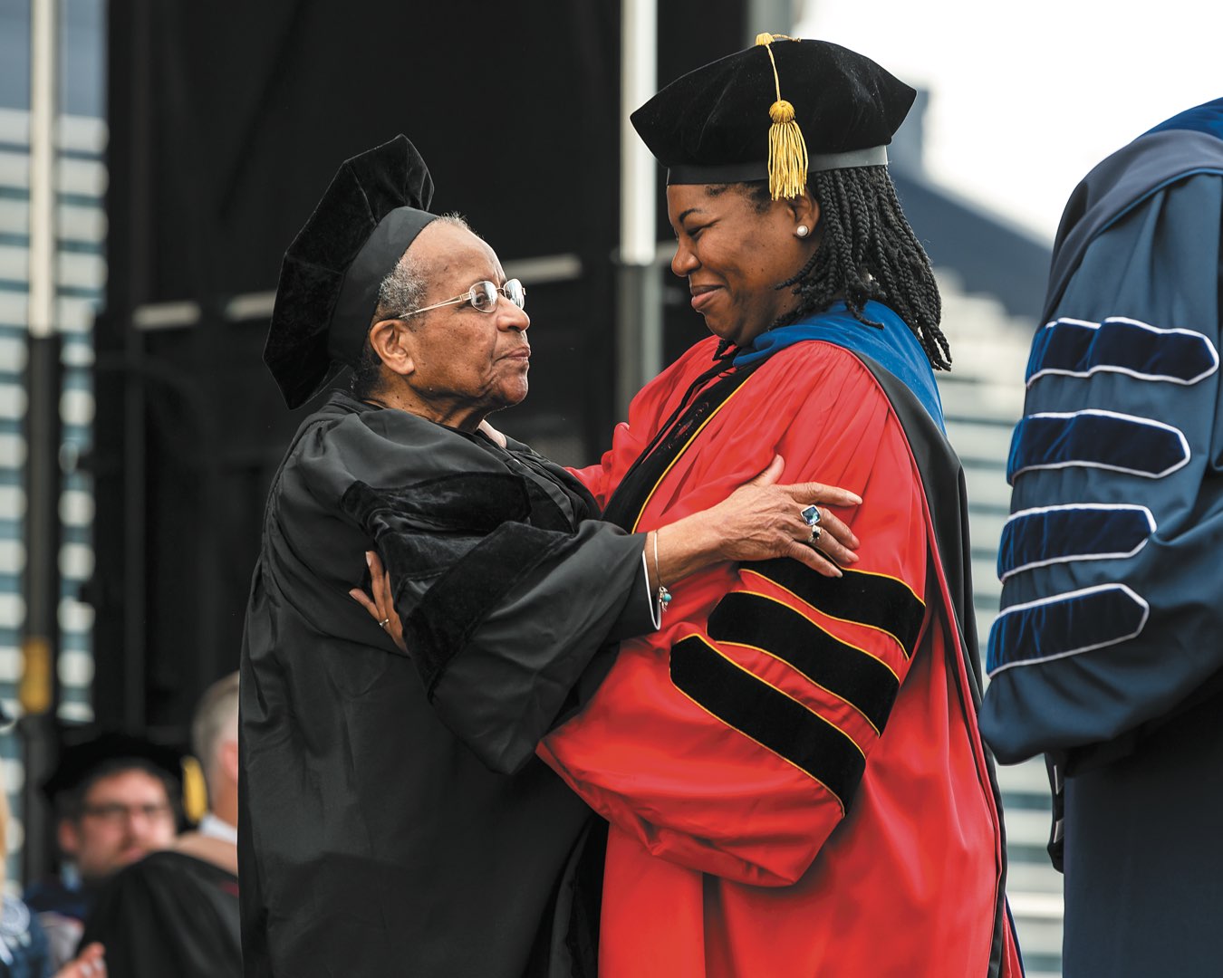 Sister Cora Marie and Dr. Shannen Dee Williams embracing at Commencement in graduation regalia