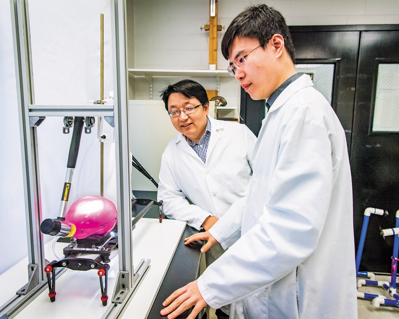 Dr. Qianhong Wu and PhD student Ji Lang wearing white lab coats testing the smart brain model in the lab
