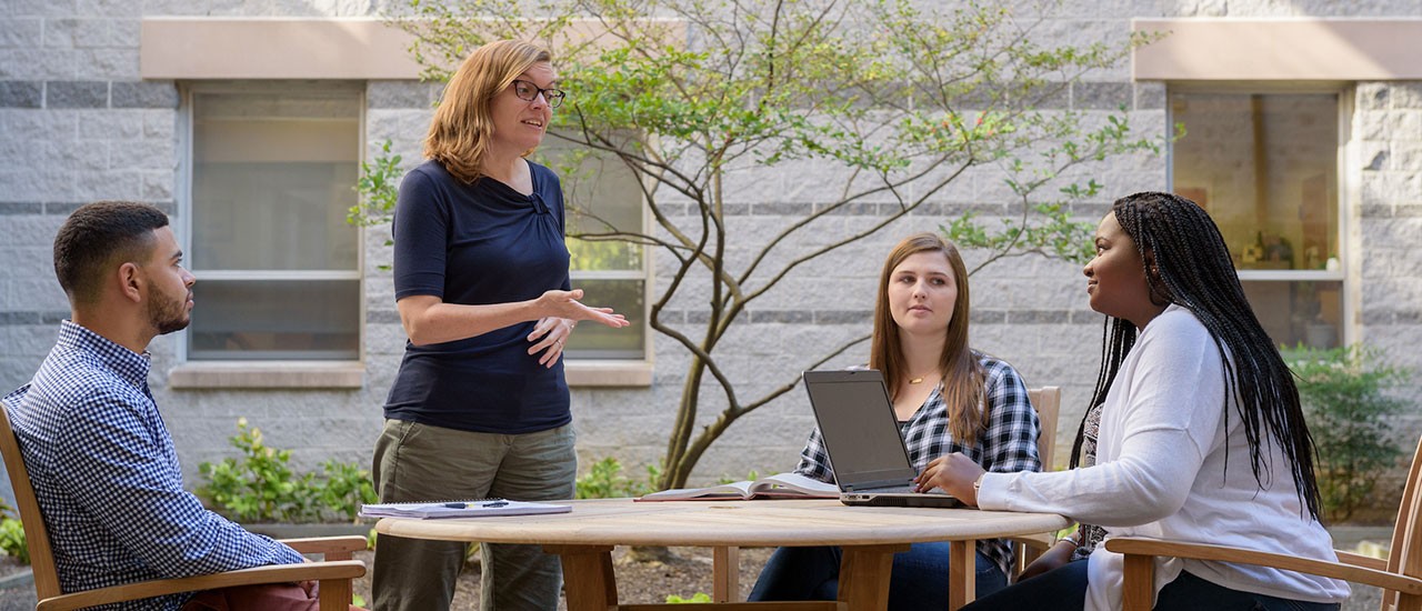 Professor and students having a discussion outside. 