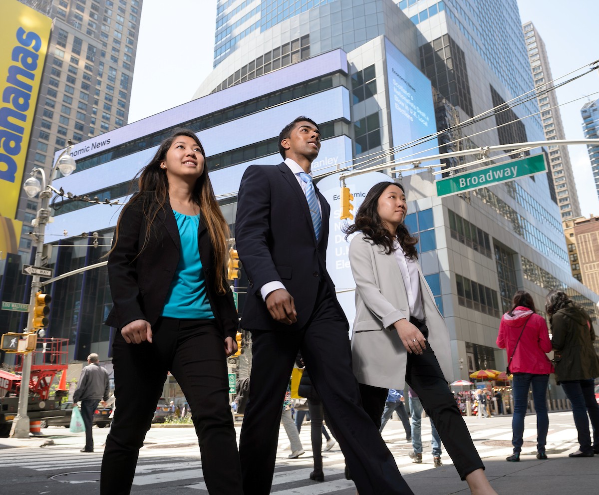 Image of three Villanovans in business attire walking down Broadway 
