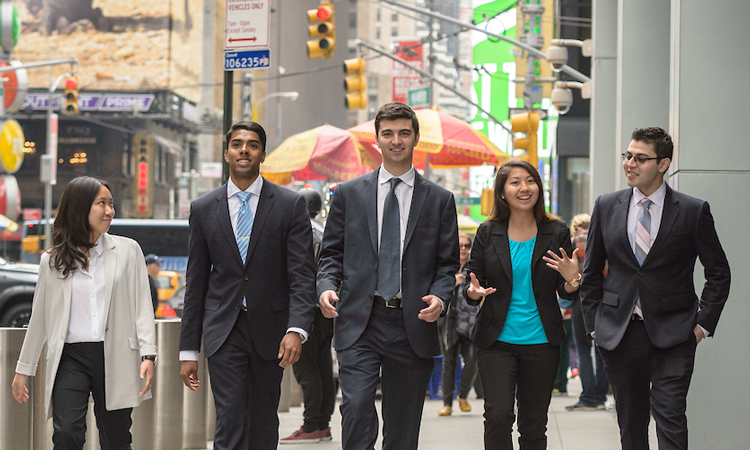 Students in business attire walking down a street in NYC