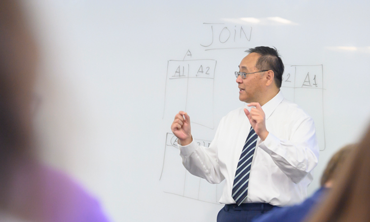 A professor teaching in front of a white board