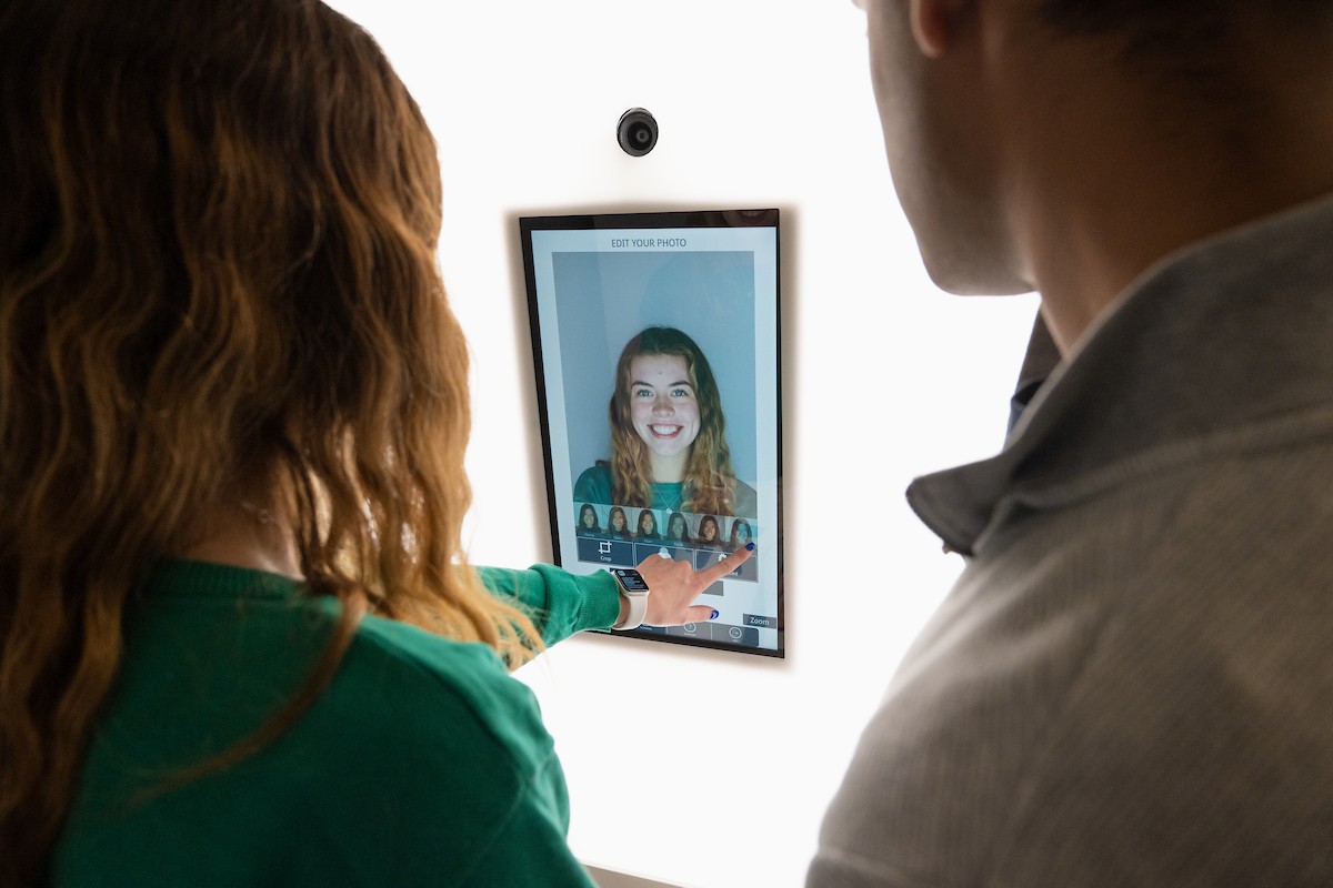 Two students looking at a screen with an image of one of the student's headshots displayed on it.