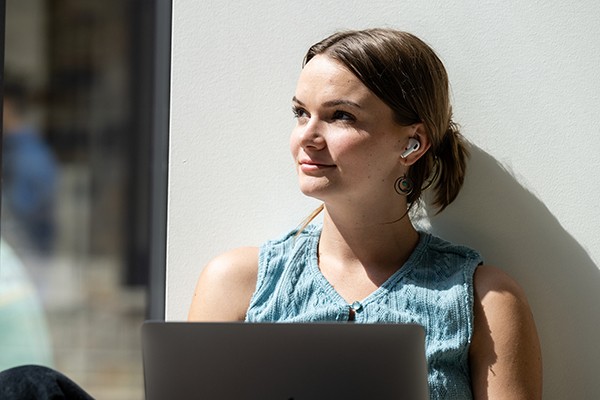 student sitting with laptop looking into the distance