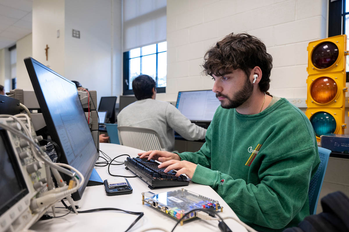 A student working on a computer with a traffic light behind them