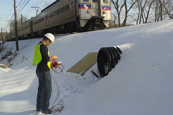 Michael Pluimer, graduate of Villanova's doctoral program in engineering, works on a project by train tracks.