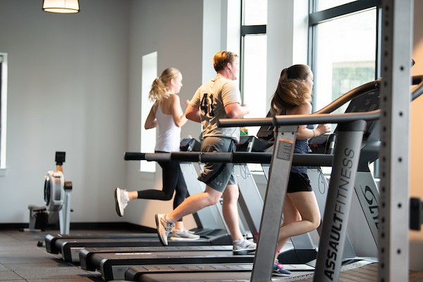 Three students running on treadmills.
