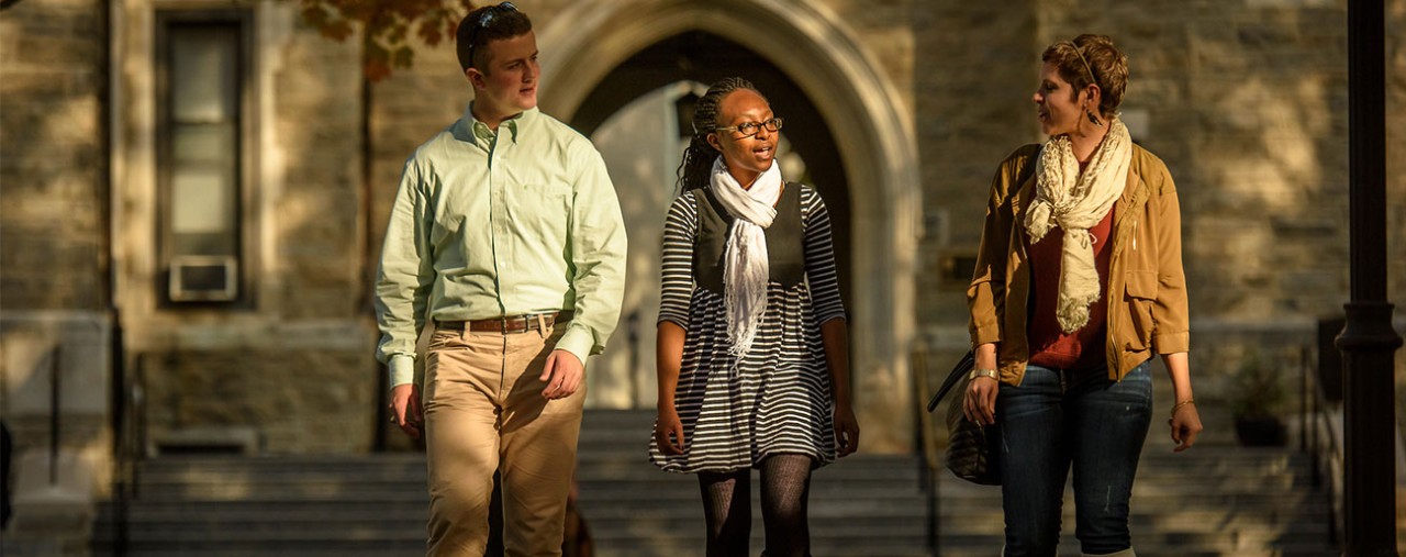three graduate students walking on campus