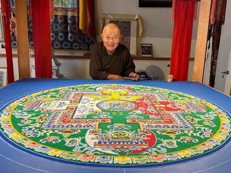 The Venerable Lama Losang Samten standing behind a Medicine Buddha mandala.