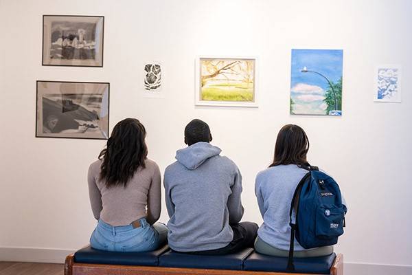 Three people looking at art in a gallery.