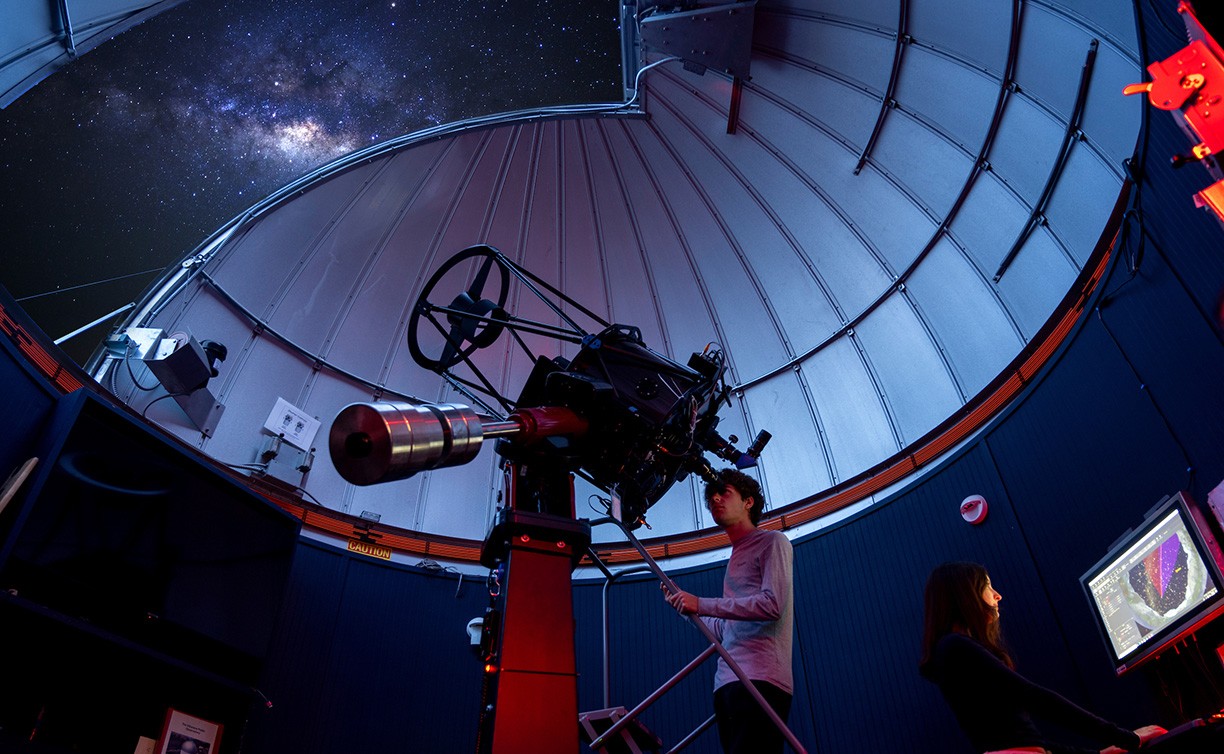 A student in the astronomy observatory looks into the night sky through a telescope. A student in the astronomy observatory looks into the night sky through a telescope.