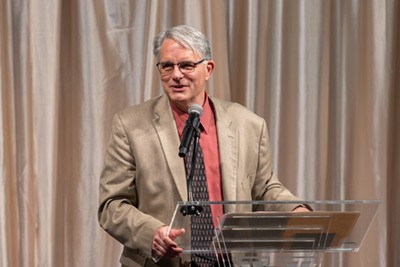 Mark Doorley, PhD, presenting at a podium. Mark Doorley, PhD, presenting at a podium.