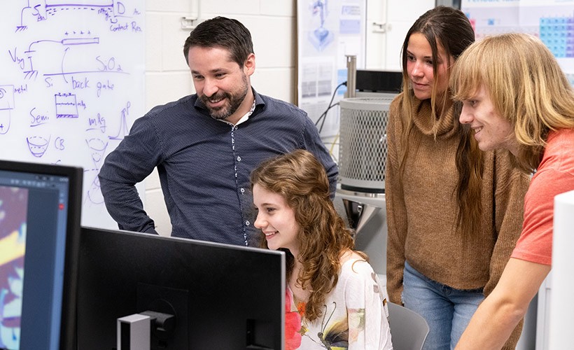 Physics professor works with students on research.