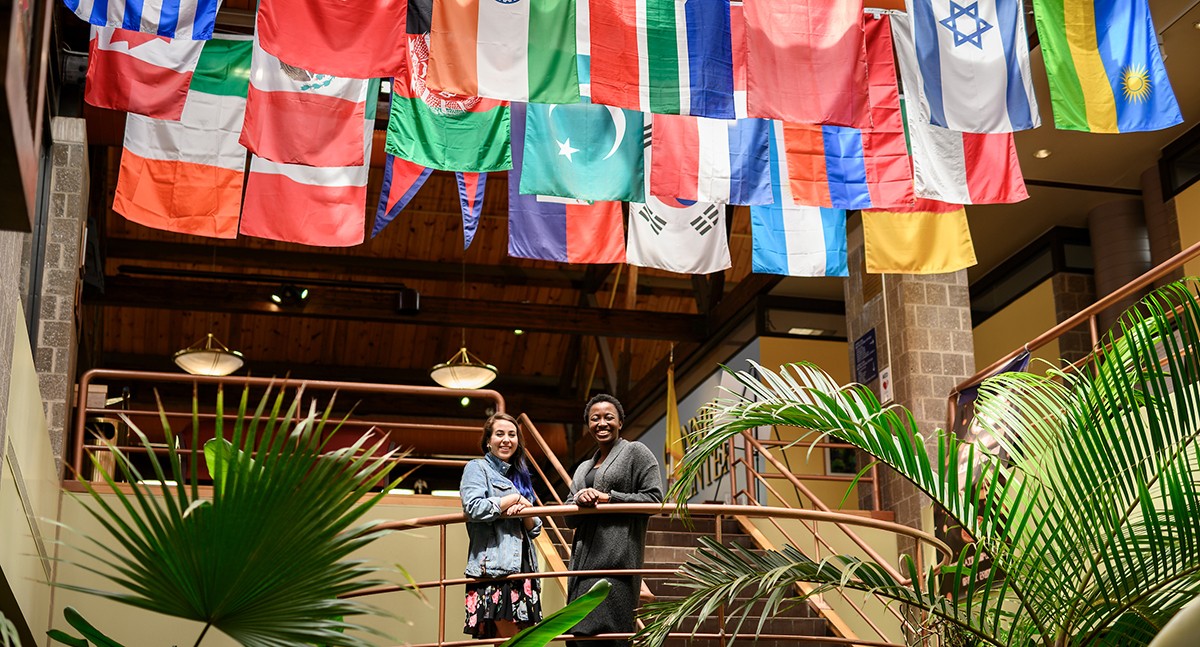 Students standing underneath the flags of the home countries of international students in the student center