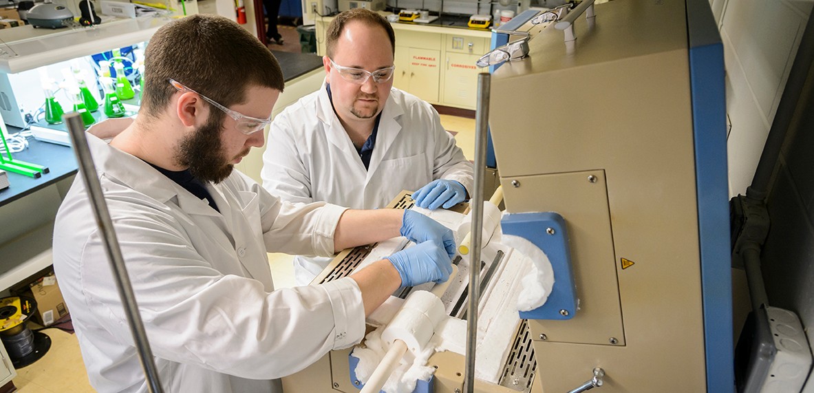 Chemistry graduate student and faculty member working with equipment in a lab