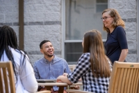 Graduate liberal studies students talking with a professor in a campus courtyard