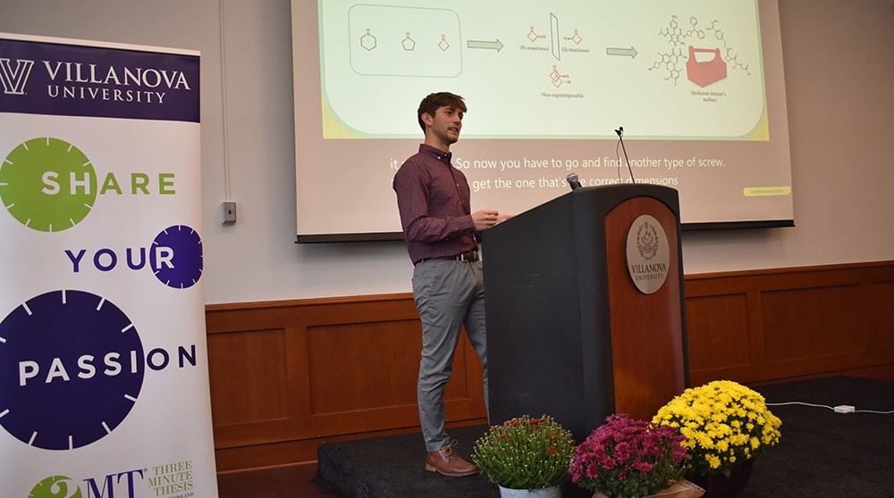 Graduate student presents on stage at the fall research symposium
