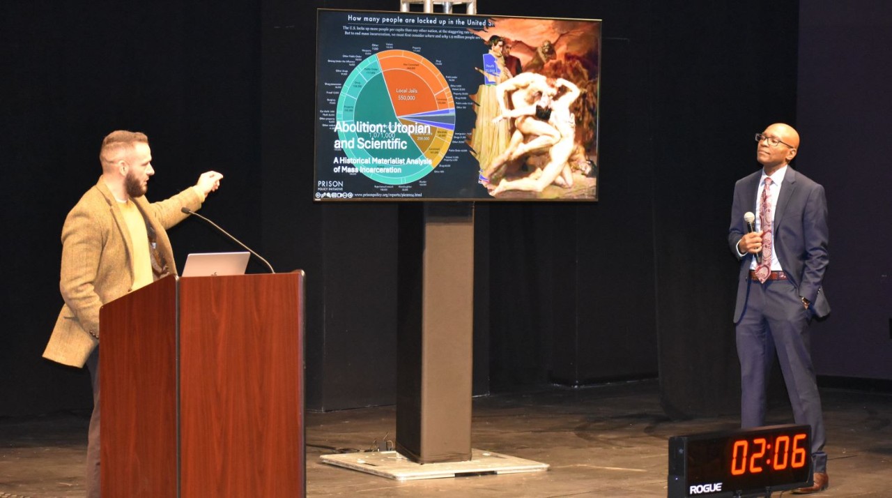 Graduate student presents on stage at the fall research symposium