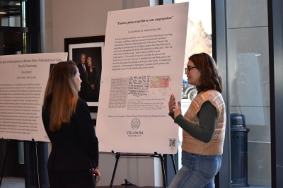 Graduate student explains the research displayed on a poster