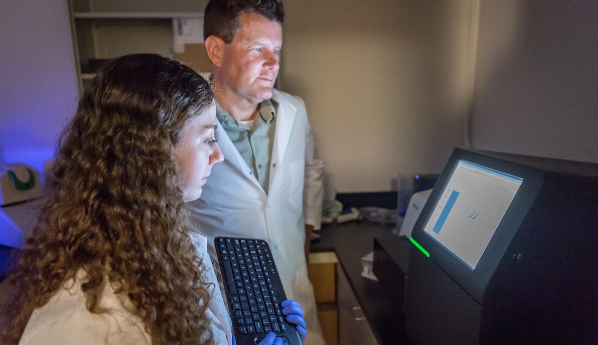 Graduate Biology student and faculty analyzing data in lab