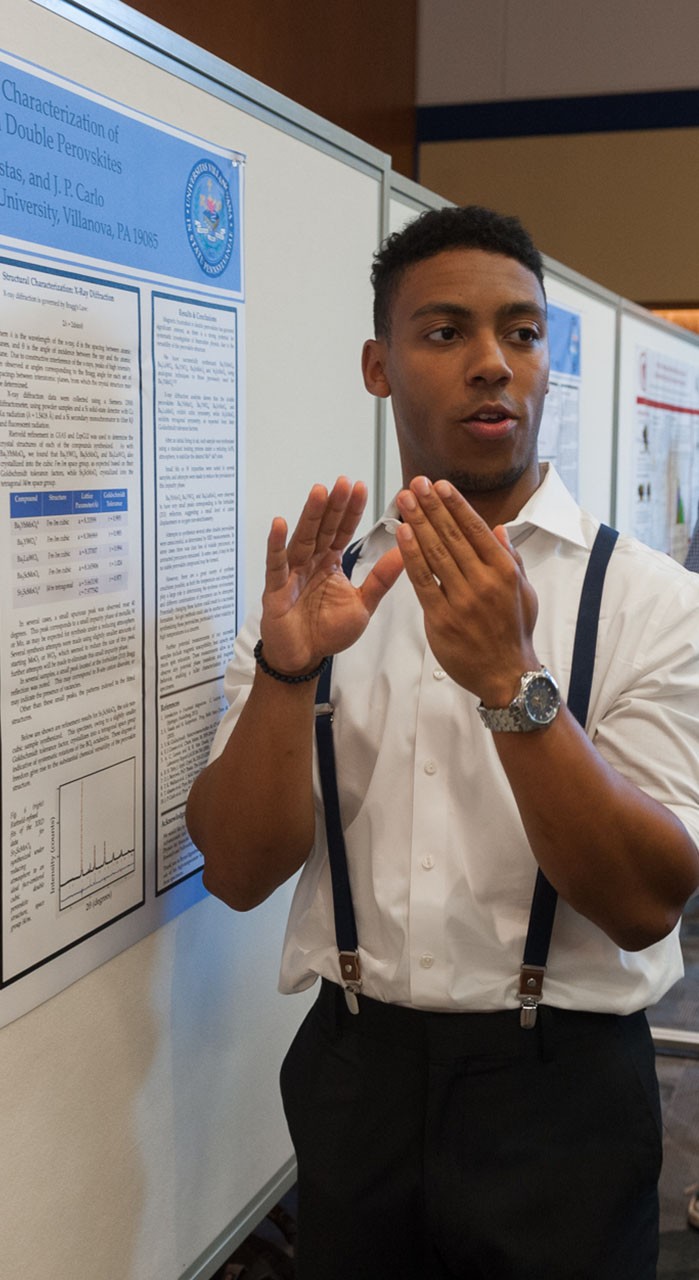 A student presents his findings at an undergraduate research poster session.
