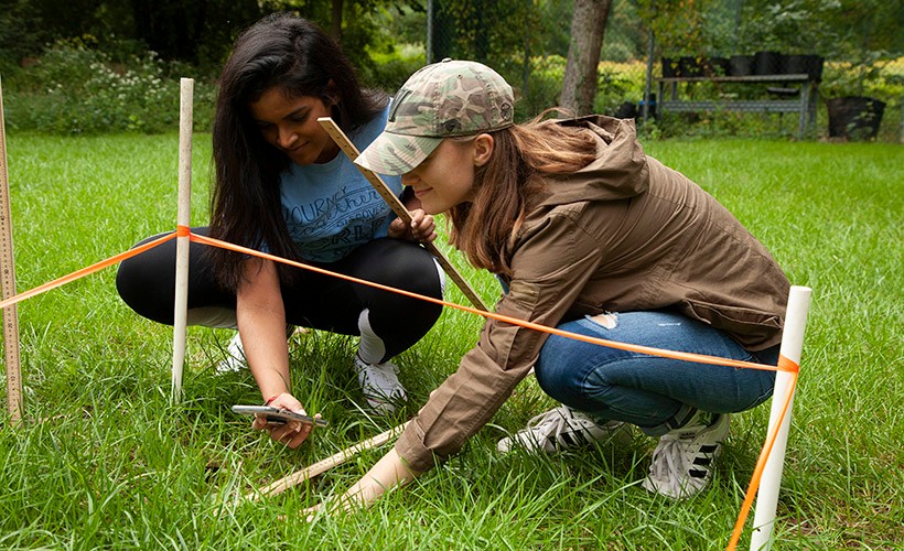 Two students conduct research in the field.