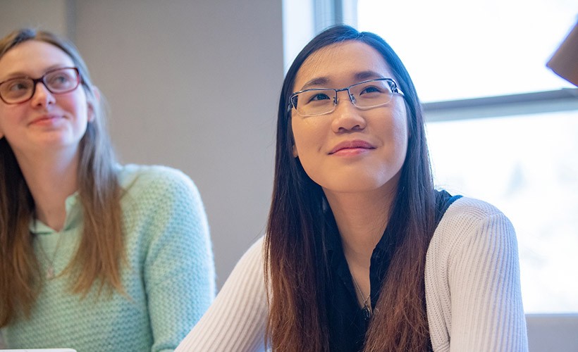 Two female students listen intently to a lecture.