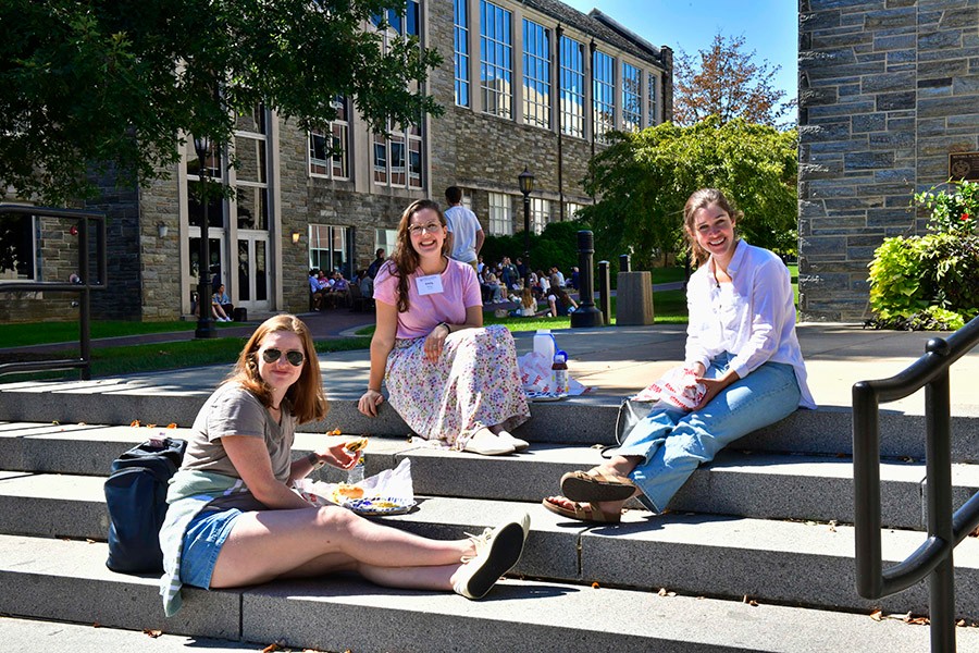 Three Humanities alumni sitting outside eating lunch.