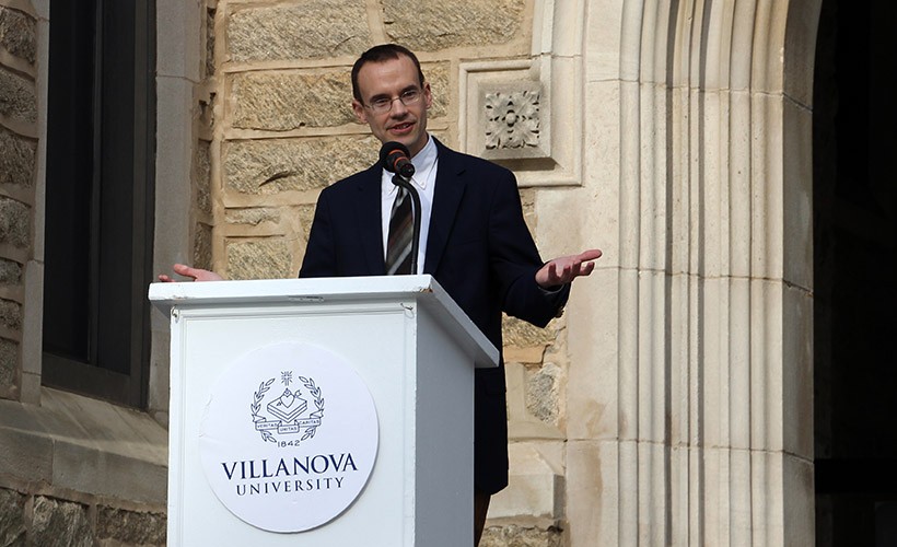 Speaker stands at podium giving lecture