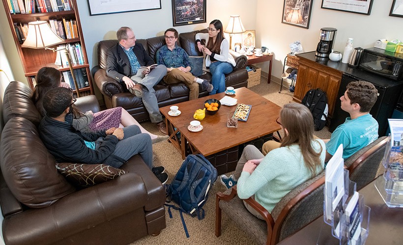 Students and faculty sit in the Humanities lounge for a discussion.