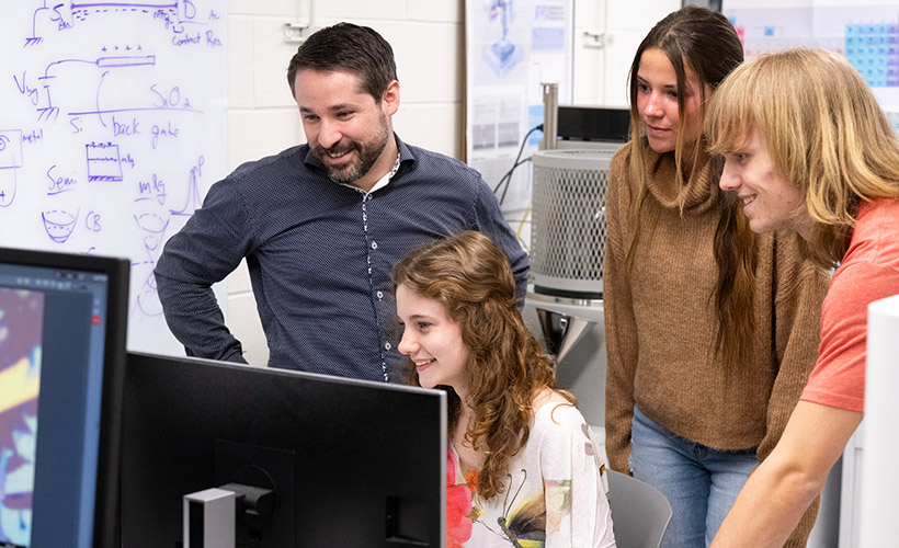 Physics students works in lab with professor Scott Dietrich. 