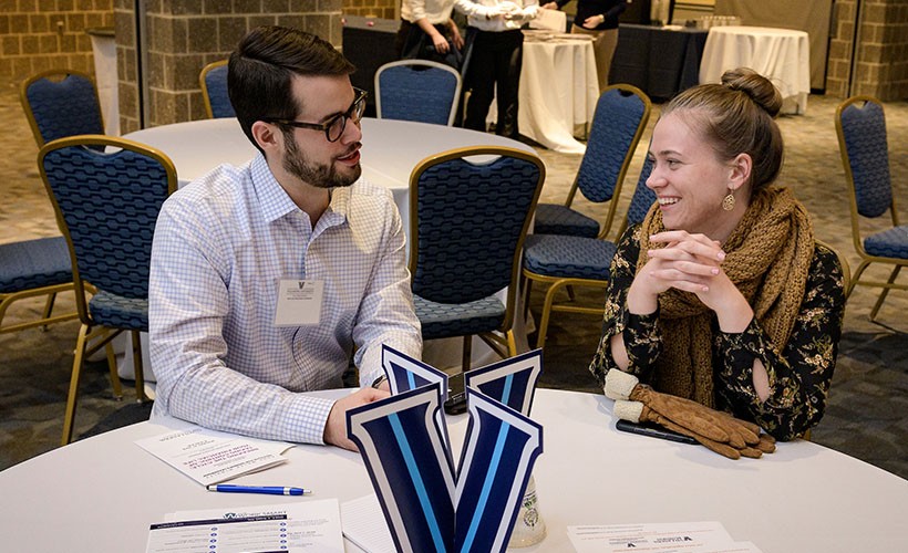 Two alumni sit together at a networking event.